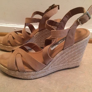 Tamaris sandaletter med kilklack i storlek 39 - Äkta Tamaris Sandaletter i kilklack. De är aldrig använda och är i äkta läder. Perfekt till sommaren😊! Skorna har en beige/ljus brun färg. Mer bilder kan skickas om så vill🌸 