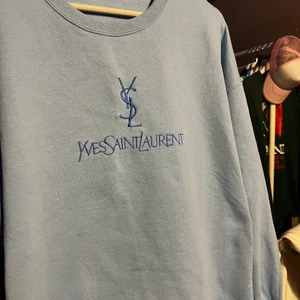 YSL Spellout crewneck - Ljusblå ysl spellout tröja köpt på second hand för nåt år sen, i storlek L. Mest hängt i garderoben HMU för fler bilder eller frågor😄
