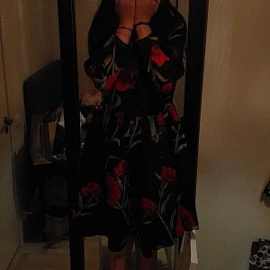 Formell klänning med rosor - En supergullig svart klänning med många lager med supersnygga stora röda rosor. Perfekt för formella evenemang, sommaren, picnic OSV.