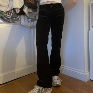 Svarta y2k byxor lågmidjade sammet raka - Svarta lågmidjade raka byxor i sammet med breda bältesöglor, en stor knapp längst fram, en liten ficka där fram samt vanliga fickor fram och bak 🖤🖤🖤Såå tidigt 2000-tal och i och med färgen passar till allt!