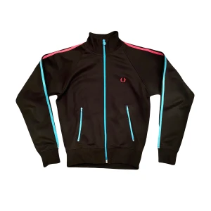 Fred perry zipup tracktop - As fet o unik fred perry track i perfekt skick. Svart med Blå dragkedjor o blå o rosa ränder. Sitter som en smäääcckk, är i storlek S men sitter mer som en XS🌺💋💥🙏🏼