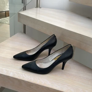 Michael kors pumps - Pumps från Michael kors. Svarta med gulddetaljer. En defekt bak på högra hälen även vissa tecken på användning på insidan.