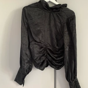 Svart blus med hög hals  - Blus med hög hals som är ”plisserad” i magen