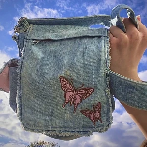 Axelväska - En axelremsväska i jeansmaterial men rosa insidor. Fyra fack + ett stort och långt justerbart band. Pm för fler bilder eller eventuella frågor