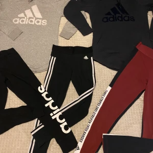 Adidaspaket, small/medium - 2 tröjor, en mörkblå och en grå. ”Sammet” tryck. Storlek M. Ena snöret på gråa tröjan är ful, se sista bild.  2st svarta leggings, storlek small. Okej skick 1st röd/mörkblå leggings, lika färg som den blåa tröjan. Nyskick, storlek small  
