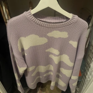 Stickad tröja från Asos, lila, storlek L - Cool tröja från Asos med molnmotiv i färgen lila, bra skick, använd ca 3-4 gånger. Storlek L