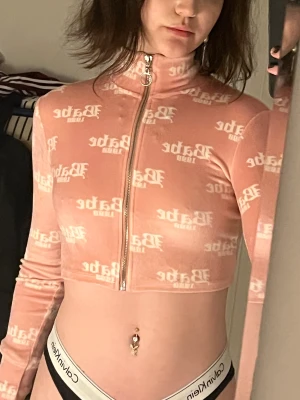 Babe fleece zip-up från Bershka - En härlig rosa fleece topp med tryck från bershka!🌸🌸 Den är i storlek XS men är rätt så stretchig! Använd typ 2 gånger. 