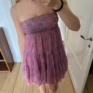 Blommig klänning - Säljer denna såå fina bandeauklänning med blommor. Den sitter uppe väldigt bra med hjälp av resår. Storlek xs men passar även s.🌟