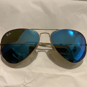 Pilotsolglasögon Ray-ban - Blåa pilotsolglasögon från märket Ray ban. Relativt nya endast använda ett fåtal gånger och är i gott skick.   Nypris cirka 1200kr men säljs här för 500kr.  Jag kan mötas upp i Stockholm men även skicka solglasögonen, dock står du för frakt.
