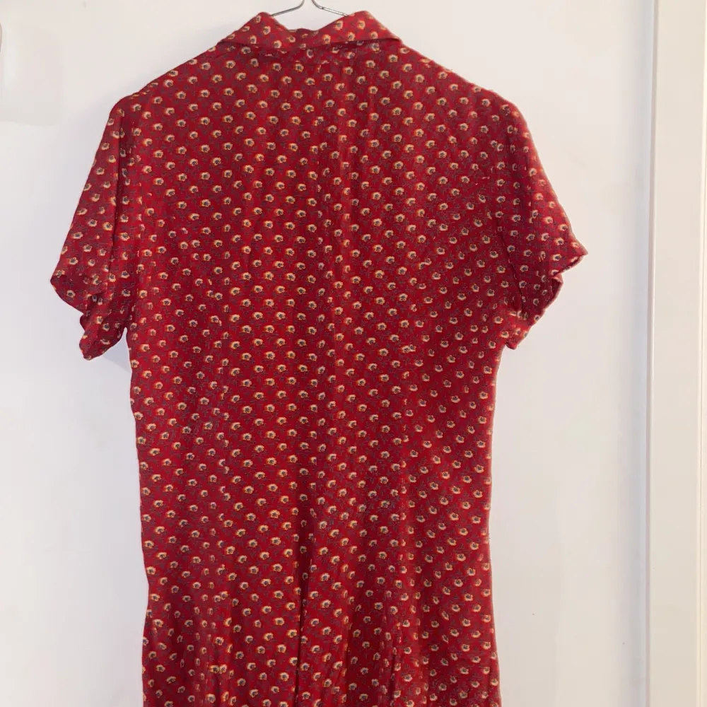 blommönstrad röd långklänning, med röda knappar, 100% viscose, bra skick. Klänningar.