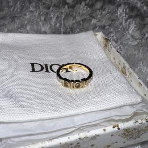 Säljer min äkta Dior ring. En av Diors mest klassiska ringar med guldbelägg, vita kristaller som klär ringens båda sidor samt Dior loggan i mitten. Tyvärr aldrig fått använda den då den är för liten för mig. Presentask, prislapp samt dustbag medföljer