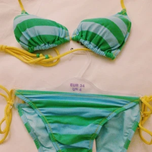 NY + OANVÄND Randig turkos/grön/gul bikini. Strlk: 34/XS. Felfri. Retro. 90-tal. - NY + OANVÄND randig turkos/grön/gul bikini. Retro-bikini från 1990-talet som aldrig kom till användning och förvarats väl sedan inköpet. Storlek: 34/XS. Lappar/tags sitter kvar sedan inköpet. Felfri.