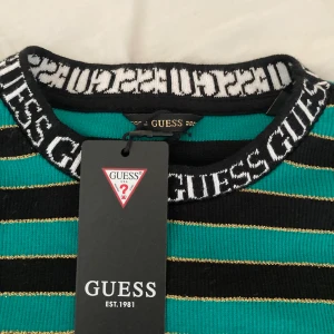 Guess randig tröja med gulddetaljer - Helt oanvänd tröja från guess i turkos o svart, samt små guldiga ränder. Passar perfekt för mig som vanligtvis har Xs i toppar💕