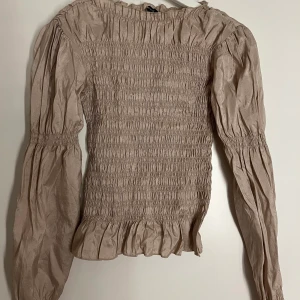Topp - Säljer denna guldiga topp från Gina tricot! Massor av veck som formas fint💕använd en gång.