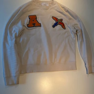 Axel Arigato Tröja Stl M - En Axel Arigato tröja i beige som är lite stor i passform så skulle även kunna passa dom som är vana vid L så väl som dom som har mest M. Tröjan är i bra skick och sparsamt använd då jag växte ur den snabbt.