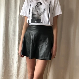 Kjol i skinimmitation  - Kjol i skinnimmitation köpt på HM. Stretchig i midjan vilket gör att man kan stoppa in en tjocktröja om man vill. Har en liten fick färgfläck på framsidan (se bild) - syns knappt då kjolen är veckad när man bär den! 