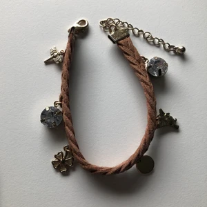 Armband med berlocker🌿🤎💎✨ - Ett fint flätat armband med olika berlocker, super gullligt och stilrent🤎! Säljer då den inte kommer till användning.(frakt med frimärke ligger på 14kr, billigare frakt)!
