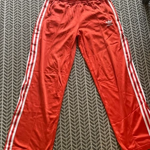 Vintage Low Waist Adidas Track Byxor - Jätte balla Adidas Track Byxor! I en jättefin orange färg som är perfekt till sommaren! Är lite korta på mig som är 174cm långa. De är raka/utsvängda nedtill och lågmidjade! Det finns två dragkedjor nedtill, man kan ge de slits.