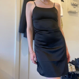 Svart glansig klänning - Svart glansig klänning (satin-liknande) från Na-kd i storlek 34. Säljer då en är lite tight över bysten för mig. Använd fåtal gånger så i fint skick! Kan mötas upp, annars står du för frakten