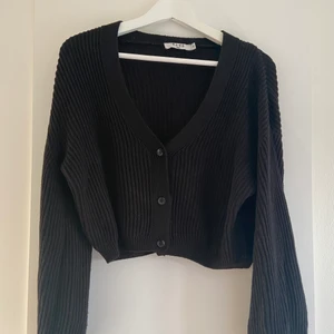 Svart stickad kofta - Tidlös svart stickad kofta från NA-KD i storlek XS. Säljer då den tyvärr inte kommer till användning. Köparen står för frakten.