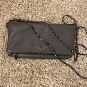 Zadig&Voltaire  väska  -  Äkta zadig väska i storlek meddel.  I bra skick och allt, inga repor eller slitningar. Kommer med båda kedjorna alla magneter funkar och alla dragkedjor funkar som de ska. Köpte väskan från boozt.  Kostade 3000kr. Buda gärna!! 