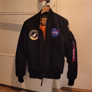 Alpha Industries NASA-jacka - NASA-jacka storlek M. Jag är 180 cm och normalbygd och på mig sitter den bra, men lite i tajtaste laget. Passar nog bäst om man är 170 - 182 cm. Jag har använt jackan tre gånger, så den är nästan i nyskick. Nypris: 1299 kr.