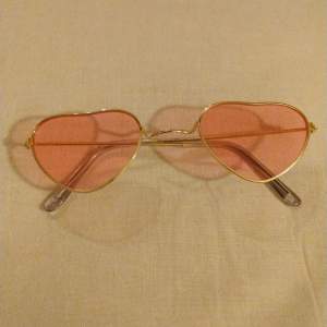 Hjärtformade solglasögon med rosa glas och guldiga bågar! Passar så bra som utklädnad- eller bara för att se världen genom ett rosa skimmer 💗