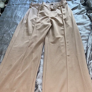 Kostymbyxor beige  - Köpta från fashionnova. Ett par kostymbyxor med knäppe där fram och dragkedja där bak, vida i benen.