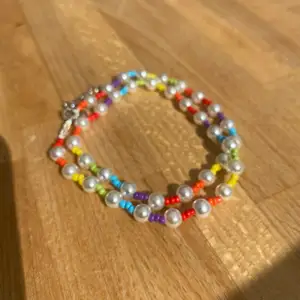 Ett super fint halsband med vita pärlor och regnbågens färger i små pärlor!