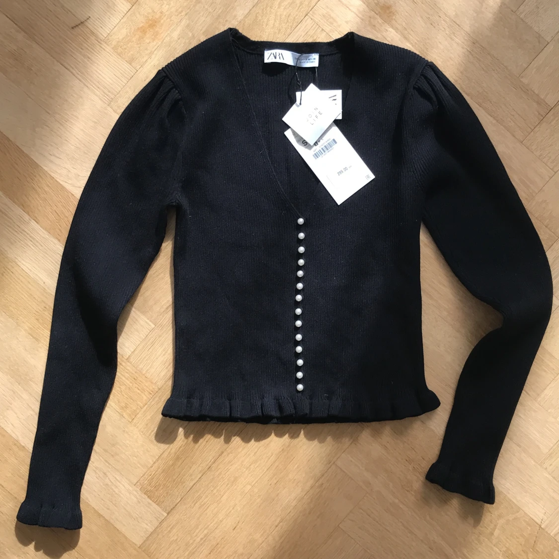 Kofta med pärlemorknappar och volang