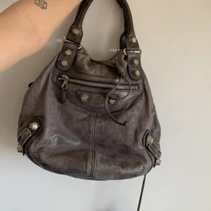 Balenciaga pompon grå - En äkta balenciaga i en så snygg nött grå färg. Har tyvärr inget närhetsbevis men detaljerna går att kolla upp så att de är äkta. T.ex. dragkedjan, serienumret, stygn etc. Inga skador eller defekter