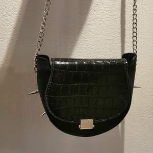 En svart handväska med långa nitar på undersidan. Säljer pga inte används. Säljaren står för frakten. 