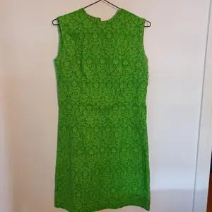 Grön vintageklänning i jättefint skick! Dragkedja bak. Dem är märkt stl 44, så jag skulle säga att det är som stl M. Den är ca 94 cm lång och är 42 cm rakt över bysten. Frakten ingår.