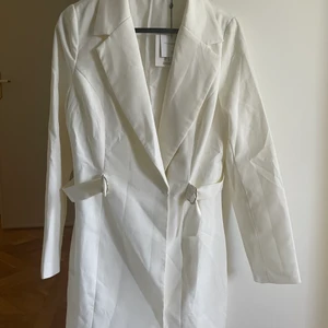 Kavajklänning - Vit kavajklänning från missguided.  Skulle varit en studentklänning men blev inte så. Aldrig använd och lapparna finns kvar så i väldigt fint skick!  Storlek 36 