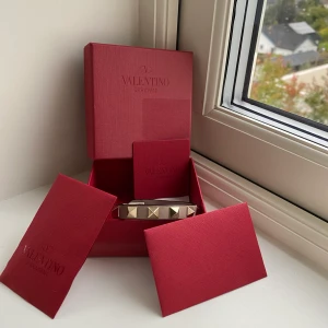 Armband Valentino - Valentinoarmband i en mörk rosabeige färg. Väldigt fint skick, använt sparsamt. Har flera liknande armband, därav kommer detta ej till användning. Guldiga nitar, tillkommer också en extra i reserv. Köparen står för valfri fraktmetod.