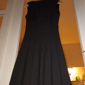 Zara Woman klänning - Svart klänni g från Zara Woman. Supersnygg modell som är lätt utställd i kjolen. Snyggt.snedskuren hals/krage. Lite tyngre tyg som gör att den faller och följer kropppen perfekt när man rör sig. Som ny! Kan skickas, spårbart mot en avgift på 51kr