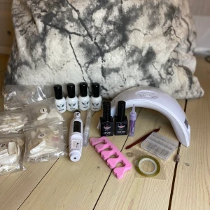 Nagelkit  - Litet nagel kit  Innehåller: : 14 små påsar med massa olika nagel tippar. :4 olika Color uv gel: ljuslila, ljusrosa, ljusrosa/beige och matt mörk lila. :elektrisk nagelfil med tillbehör till den. : en uv lampa  : Top coat, Base coat : glitter  Och mer
