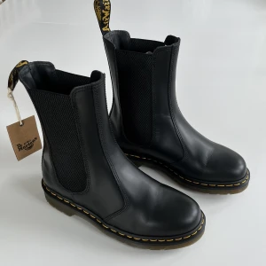 Dr Martens hi chelsea - Chelsea-boots med högt skaft i nyskick. Passar dig med 25 cm lång fot. Använda endast 3 gånger och säljs pga att de är lite för trånga. Nypris 2299:-