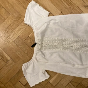 Vit blus med broderi  - En vit liten blus aktig topp med fint mönster i mitten. Den är i storlek S. 