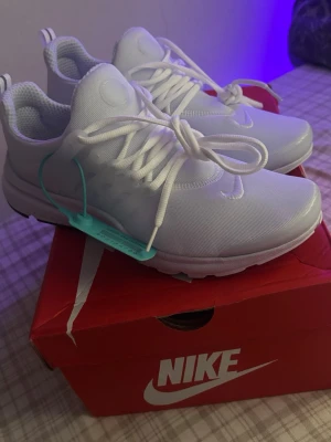 Nike prestos  - Snygga helvita Nike sneakers med låg profil och klassisk design. Skorna har mesh-överdel för bra andningsförmåga, vita snören och diskret Nike-logga på sidan. Perfekta för dig som gillar stilrena och sportiga skor.