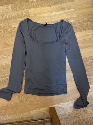 Brun långärmad topp Gina Tricot - Säljer en enkel och stilren brun långärmad topp från Gina Tricot. Toppen har en bred, fyrkantig urringning och är gjord i ett mjukt och stretchigt material som sitter tight mot kroppen. Perfekt att matcha med jeans eller kjol.