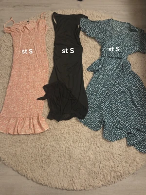 Tre klänningar i olika färger stl S, och lite annat blandat - Tre snygga klänningar i storlek S. En rosa blommig långklänning med volangkant och smala axelband, en svart ärmlös långklänning med slits och en blå kort omlottklänning med vita prickar, volang och knytband i midjan. Sen lite blandade klädesplagg, mellan 50-100kr st, hämtas i Motala🤗