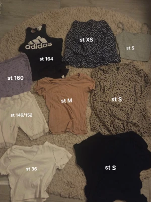 Stort klädpaket med toppar och tights - Säljer ett blandat klädpaket med flera toppar, t-shirts, linnen och ett par Adidas tights. Färgerna varierar mellan svart, grått, vitt, beige, lila och mönstrat. De flesta kläderna är barnstorlekar, 30kr/st, hämtas i Motala🤗