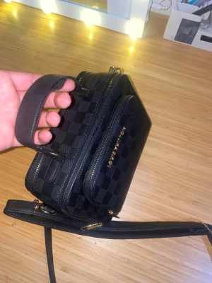 Väska - Snygg svart handväska med guldfärgade dragkedjor. Väskan har både handtag och justerbar axelrem, samt två fack med dragkedja. Handtaget har lite problem men kan fixas med att limma fast den❤️.