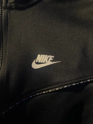 Nike tech Zip-hoodie - En svart niketech zip-hoodie. Haft den i ca 3-4 år och använt några fåtal gånger. Säljer då den blivit en aning liten på mig. Synligt använd, därav prissänkningen.