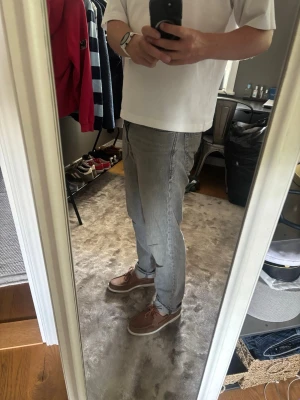 Grå jeans - Säljer ett par grå jeans med klassisk femficksmodell och raka ben. Jeansen har normal midja och är tillverkade i ett mjukt denimtyg. Perfekta för en avslappnad och stilren look.