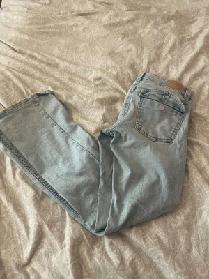 Ljusblå bootcut jeans - Säljer ett par ljusblå jeans med bootcut-modell och klassisk femficksdesign. Jeansen har en snygg tvättad look och är tillverkade i denim med lätt stretch. Perfekta för dig som gillar en avslappnad men trendig stil. SÅÅ SNYGGA! typ aldrig använda bara en ytterst liten defekt längst ner på jeansen.🌸🌸🌸