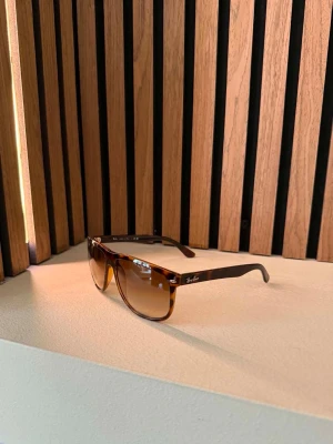 Bruna Ray-Ban boyfriend - Snygga solglasögon från Ray-Ban med brunmelerad båge och bruna tonade glas. Klassisk fyrkantig form som ger en cool och tidlös look. Perfekta för soliga dagar och passar till de flesta outfits.