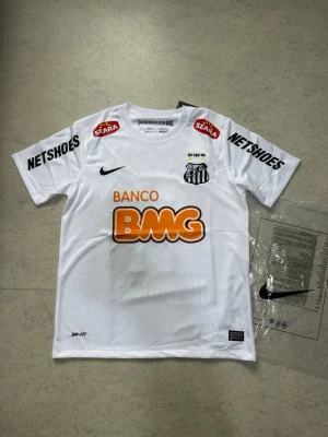 Neymar Santos  - Neymar Dos Santos T-shirt  Vit Neymar Dos Santos T-shirt med stilren design. Skön passform och bekvämt material, perfekt för både vardag och streetwear. Ett riktigt bra plagg för Neymar-fans och fotbollsälskare. Storlek S.