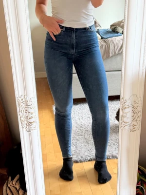 Mörkblå jeans från BikBok, strl S - Säljer ett par mörkblå jeans från BikBok med hög midja och tight passform. De är i väldigt fint skick. Jag på bilderna är 177 cm lång och bär i vanliga fall storlek S/M. ✨ Storlek: S, stretchiga ✨ Passform: Skinny med hög midja